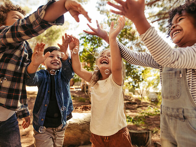 Kinder spielen mit Seifenblasen