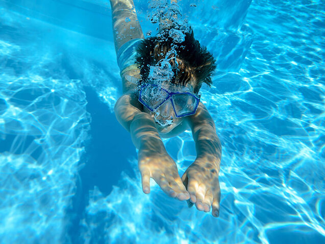 Kind schwimmt unter Wasser im Pool
